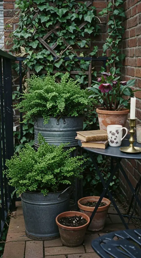 Balcony setting. A dark grey zinc container and a black wrought iron table and chair are positioned in the corner.